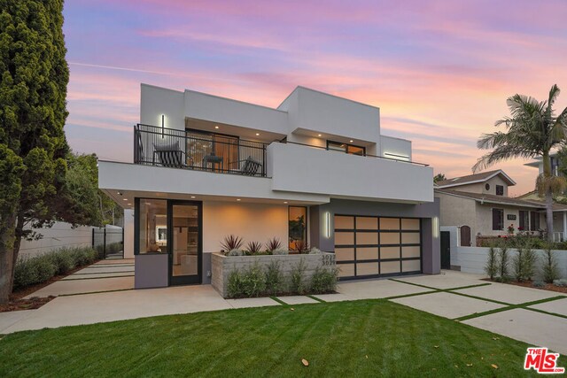 modern home with a balcony, a garage, and a lawn