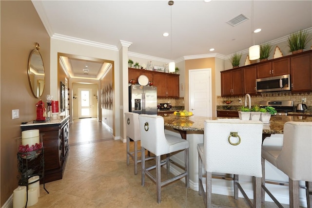 kitchen featuring pendant lighting, stainless steel appliances, stone countertops, a breakfast bar, and a center island with sink