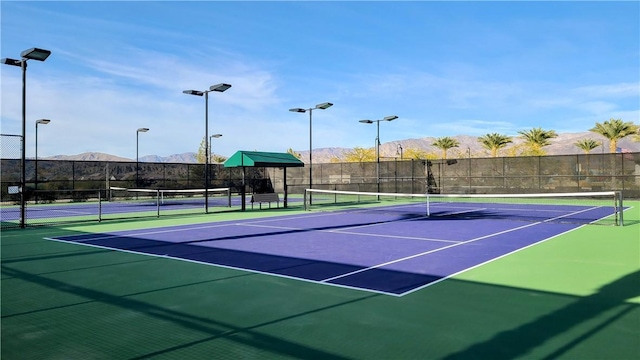 view of tennis court with a mountain view and basketball hoop