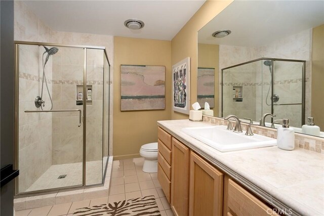 bathroom with a shower with door, tile patterned floors, vanity, and toilet