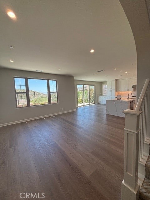 250 Canterbury, Irvine, CA 92618 - unfurnished living room with plenty of natural light, dark wood-style flooring, baseboards, arched walkways, and recessed lighting