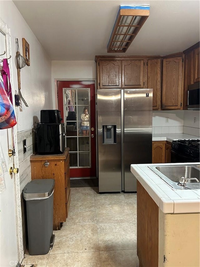 kitchen with sink, appliances with stainless steel finishes, and tile counters