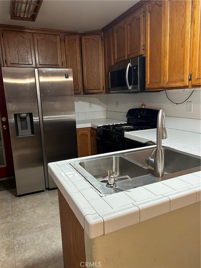 kitchen featuring tile counters, light tile patterned floors, kitchen peninsula, and appliances with stainless steel finishes