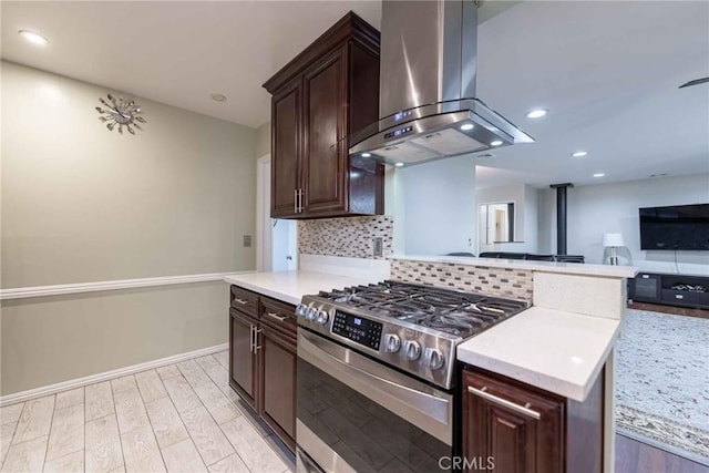 kitchen featuring dark brown cabinets, stainless steel gas range, island range hood, and tasteful backsplash