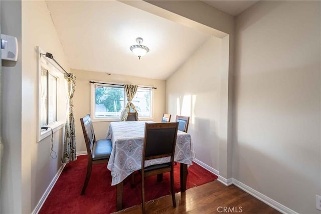 dining space featuring vaulted ceiling and dark hardwood / wood-style flooring