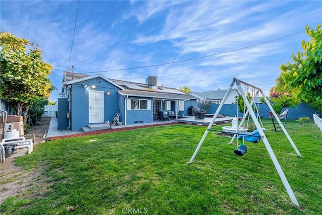 back of property featuring a yard, solar panels, and a patio