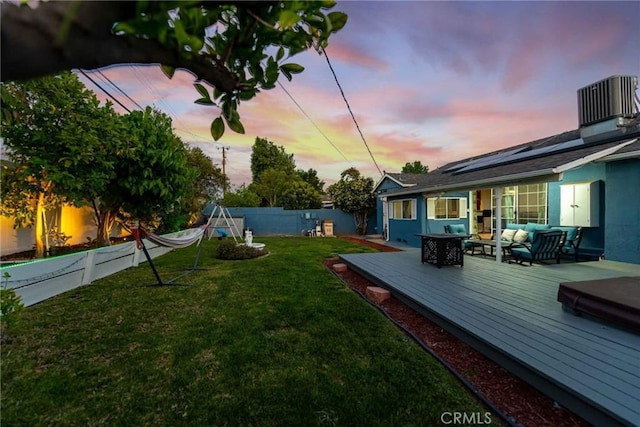 yard at dusk with central AC unit, outdoor lounge area, and a wooden deck