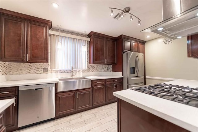 kitchen with exhaust hood, stainless steel appliances, backsplash, decorative light fixtures, and sink