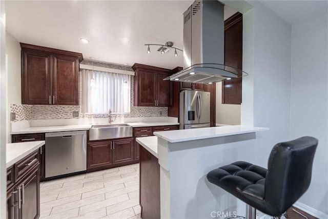 kitchen featuring island range hood, kitchen peninsula, appliances with stainless steel finishes, hanging light fixtures, and sink