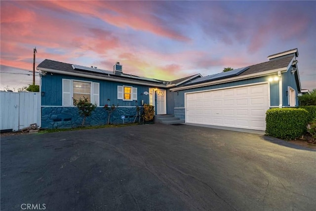 ranch-style home with solar panels and a garage