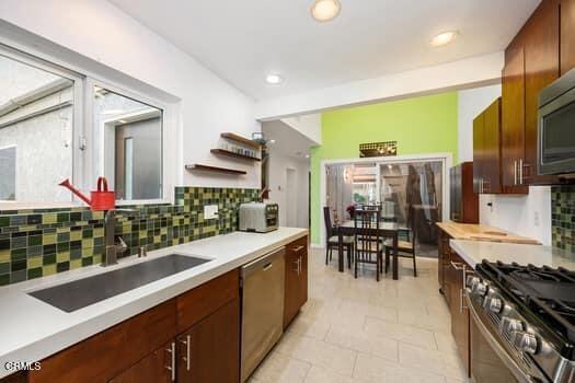 kitchen with decorative backsplash, sink, appliances with stainless steel finishes, and light tile patterned floors