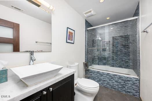 full bathroom featuring toilet, tiled shower / bath, and vanity