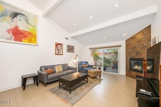 living room featuring vaulted ceiling with beams and a large fireplace