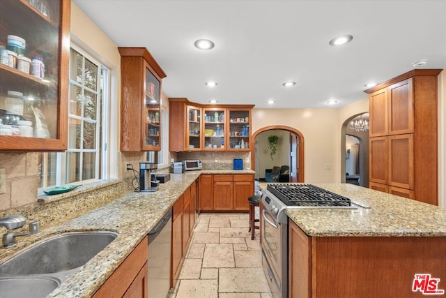 kitchen featuring light stone countertops, appliances with stainless steel finishes, decorative backsplash, and sink