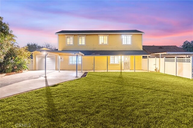 back house at dusk with a garage and a yard