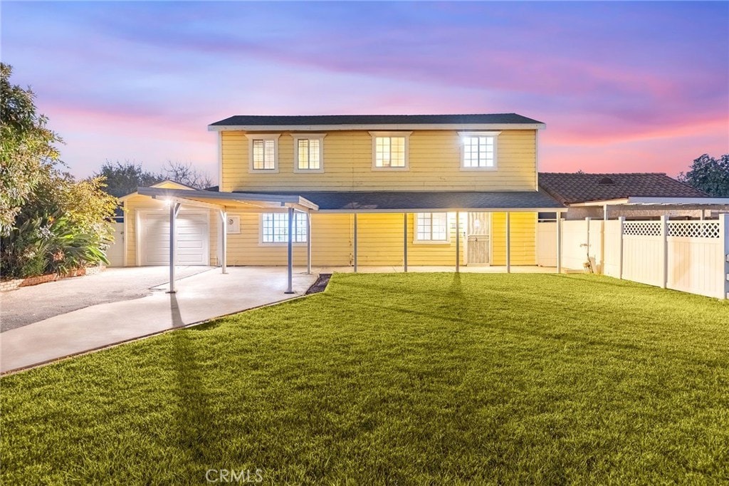 back house at dusk with a garage and a yard