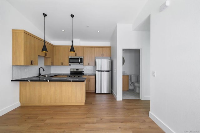 kitchen with stainless steel appliances, sink, tasteful backsplash, and decorative light fixtures