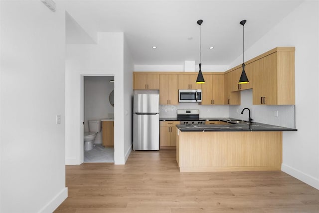 kitchen with stainless steel appliances, light brown cabinetry, sink, hanging light fixtures, and kitchen peninsula