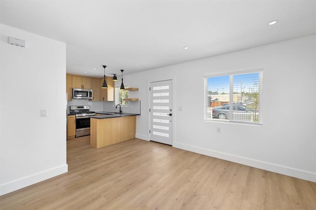 kitchen featuring plenty of natural light, hanging light fixtures, stainless steel appliances, and light wood-type flooring