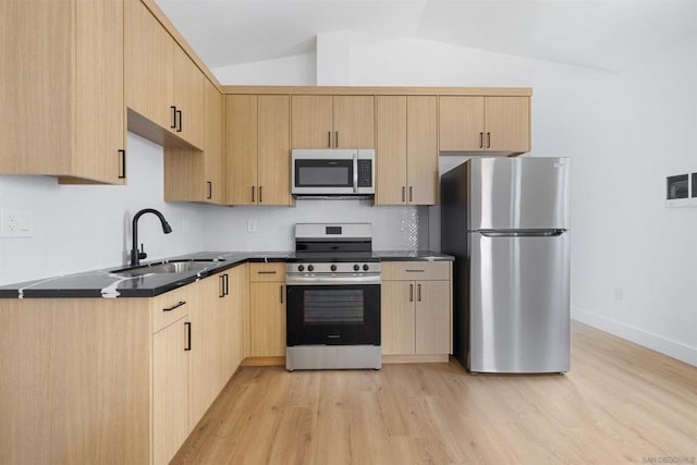 kitchen with stainless steel appliances, lofted ceiling, light brown cabinets, and sink