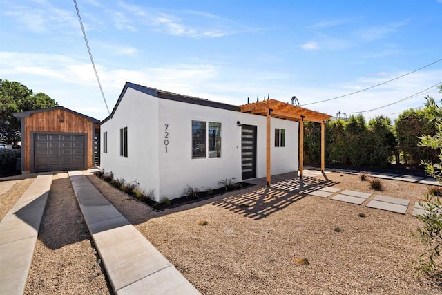 view of front of home featuring a pergola, a garage, and an outbuilding