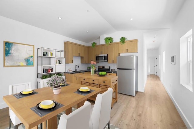 dining area featuring sink, light hardwood / wood-style flooring, and vaulted ceiling