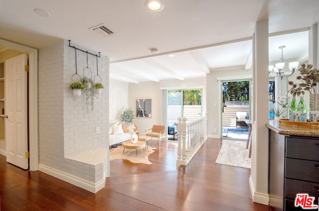 living room featuring dark wood-type flooring, beam ceiling, and a notable chandelier