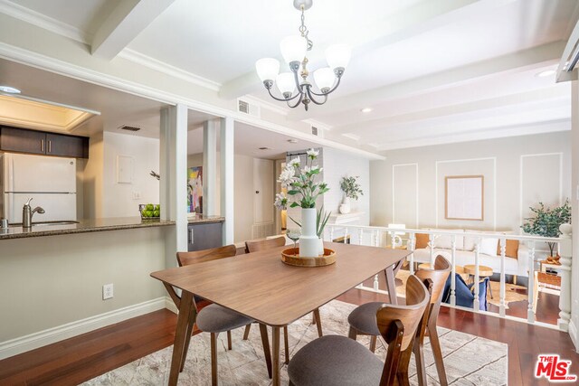 dining room featuring hardwood / wood-style floors, an inviting chandelier, sink, ornamental molding, and beam ceiling