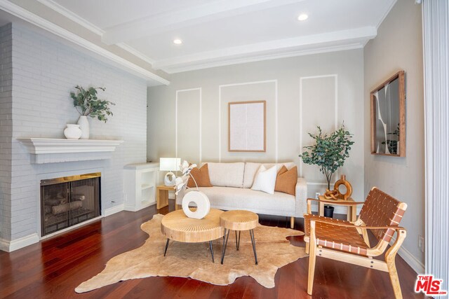 living room with beam ceiling, a fireplace, ornamental molding, and dark wood-type flooring