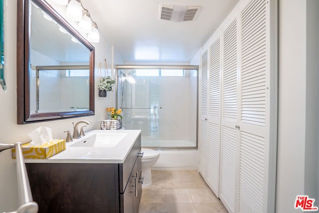 full bathroom with tile patterned flooring, toilet, vanity, and combined bath / shower with glass door