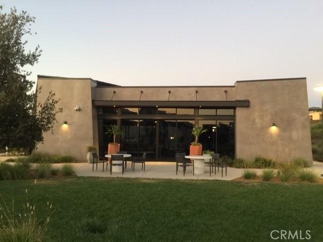 back house at dusk featuring a patio and a yard