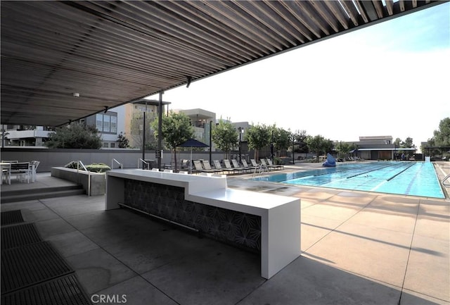 view of pool featuring a bar and a patio