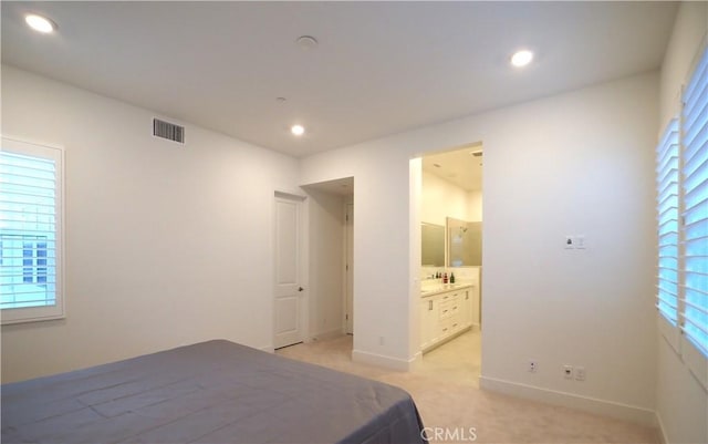 bedroom featuring light carpet and ensuite bathroom