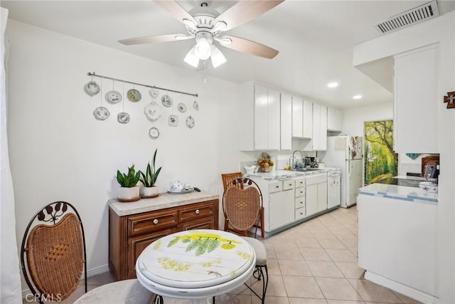 kitchen featuring white cabinets, white fridge, sink, ceiling fan, and light tile patterned floors