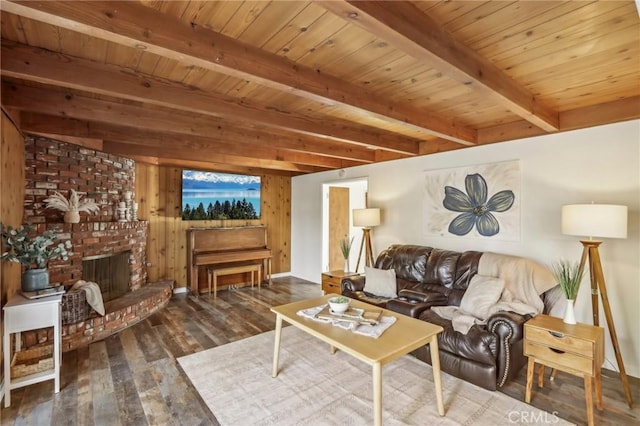 living room with dark wood-type flooring, wood walls, a brick fireplace, wooden ceiling, and beam ceiling