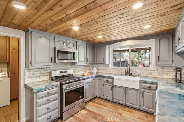 kitchen featuring washer / clothes dryer, sink, stainless steel appliances, and wooden ceiling