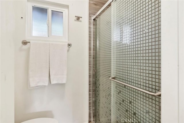 bathroom featuring a shower with shower door and toilet