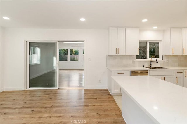 kitchen with light hardwood / wood-style flooring, backsplash, white cabinets, and sink