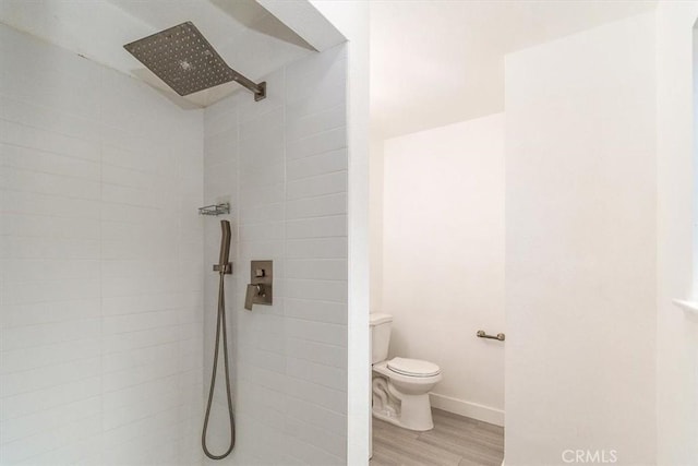 bathroom featuring hardwood / wood-style floors, toilet, and a tile shower