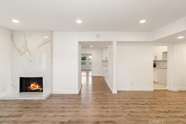 unfurnished living room with light wood-type flooring and a tiled fireplace