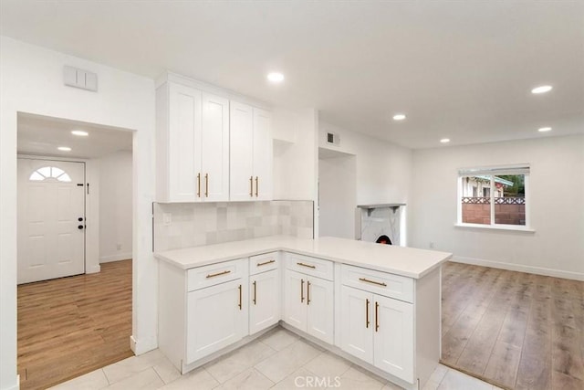 kitchen featuring kitchen peninsula, decorative backsplash, and white cabinetry