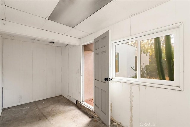 basement featuring a drop ceiling and wooden walls