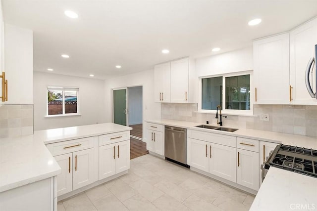 kitchen with backsplash, dishwasher, sink, and white cabinetry