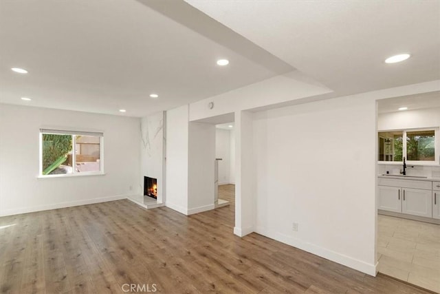 unfurnished living room with sink and light hardwood / wood-style floors