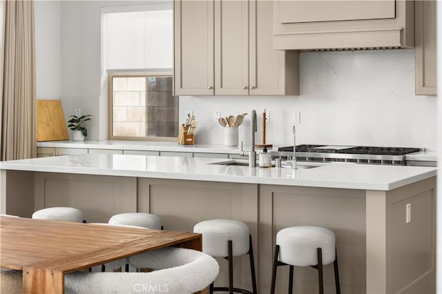 kitchen with light countertops, tasteful backsplash, a sink, and a breakfast bar