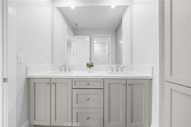 full bath with a shower, visible vents, a sink, and double vanity