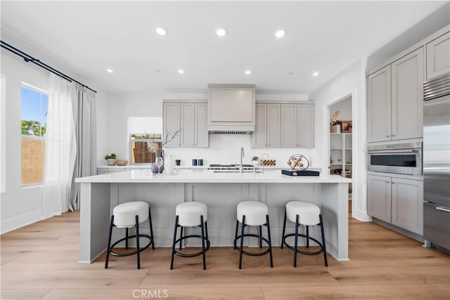 kitchen featuring an island with sink, appliances with stainless steel finishes, a wealth of natural light, and gray cabinetry