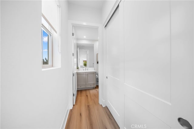 hall with a sink and light wood-style floors