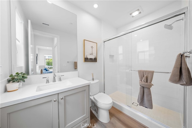 bathroom featuring visible vents, toilet, a shower stall, vanity, and wood finished floors