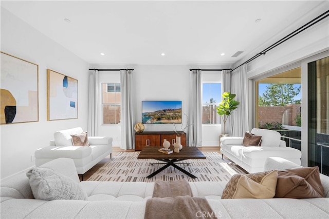 living area with visible vents, wood finished floors, a wealth of natural light, and recessed lighting